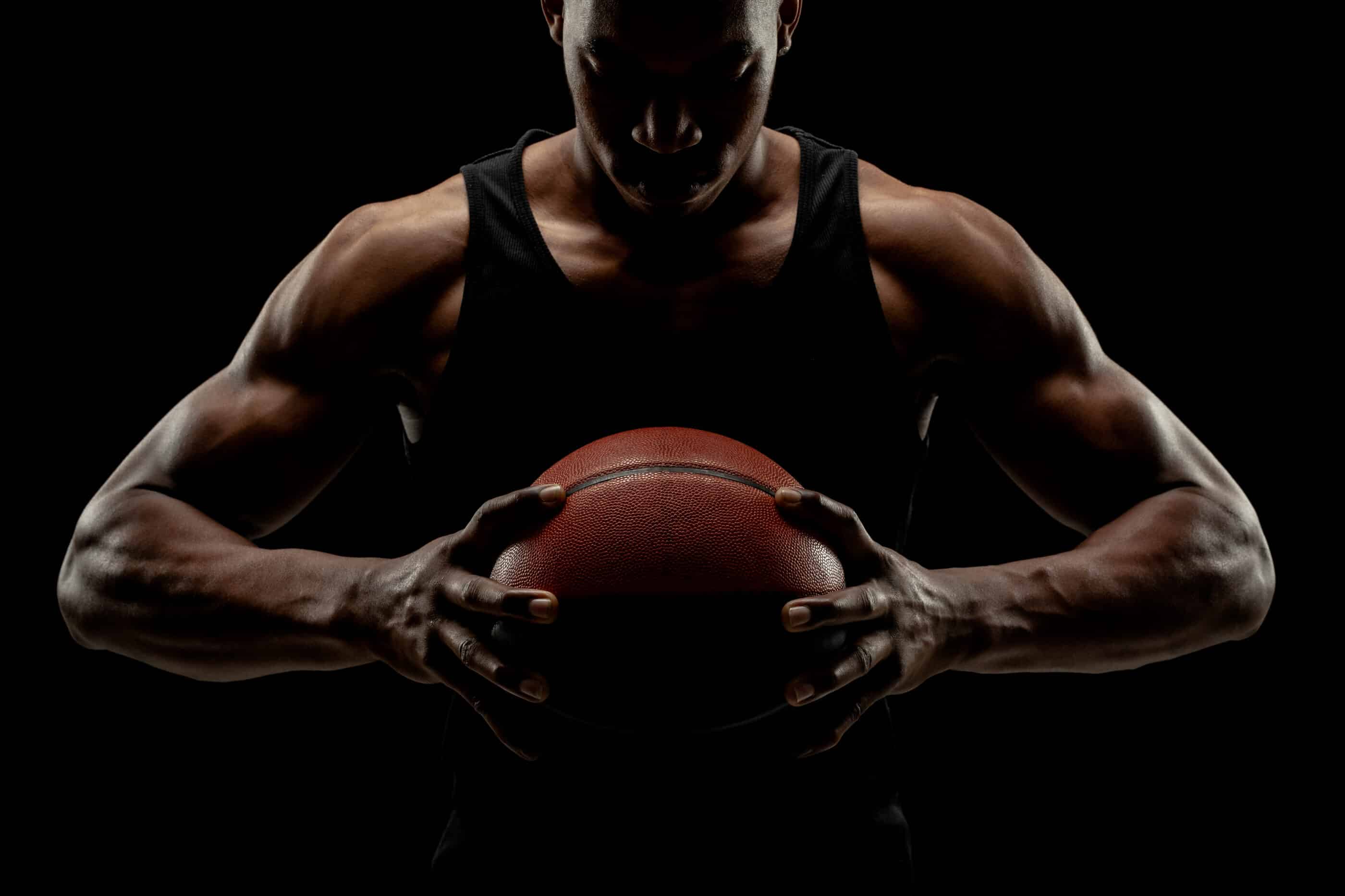 Spasenoski, N. Basketball player holding a ball against black background. Adobe Stock